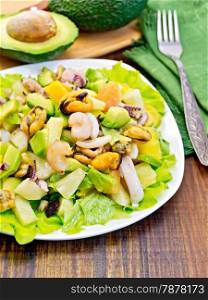Salad with shrimps, octopus, mussels and calamari with avocado, lettuce, pineapple in plates, napkin, fork, sliced avocado on a background of dark wooden boards