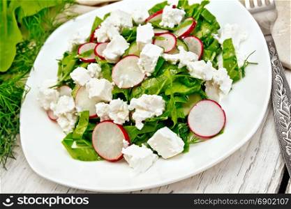 Salad with spinach, cucumbers, radish and salted cheese, dill and green onions in a white plate, a towel on the background of a light wooden board