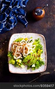 Salad with squid and avocado on white plate
