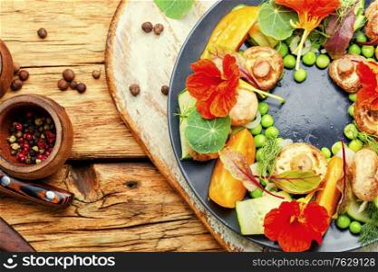 Salad with stewed mushrooms,cucumber,tomato and nasturtium on retro wooden table. Diet salad with nasturtium