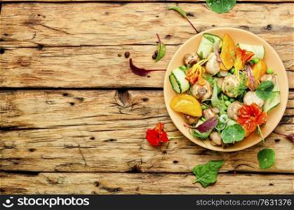 Salad with stewed mushrooms, cucumber,tomato and nasturtium on rustic wooden table.Copy space. Mushroom salad with vegetables