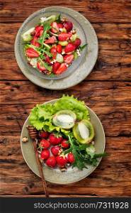 Salad with strawberry, arugula and kiwi on wooden table.Healthy diet salad. Fresh strawberry salad