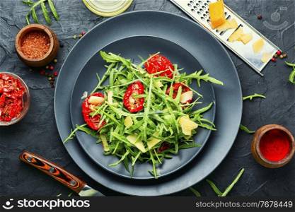 Salad with sun dried tomatoes and herbs.Bright vegetable salad on kitchen table. Vegetable salad with sun-dried tomatoes and arugula,top view