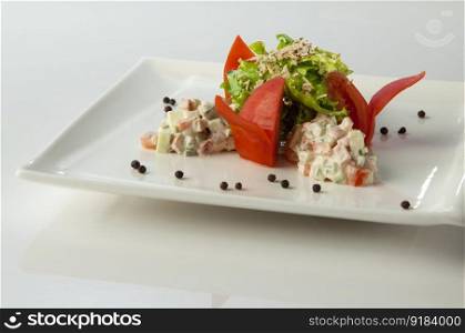 salad with tomato and mayonnaise in a plate on a white background. salad in a white plate