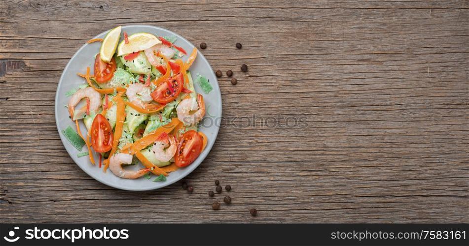 Salad with tomato, cucumber and shrimp.Healthy salad plate. Shrimp salad on wooden table