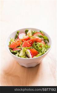 Salad with tomato, cucumber, radish, arugula and sesame seeds with olive oil