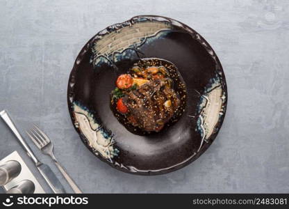 salad with tomatoes and eggplant in a plate on a gray background. the food, the view from the top