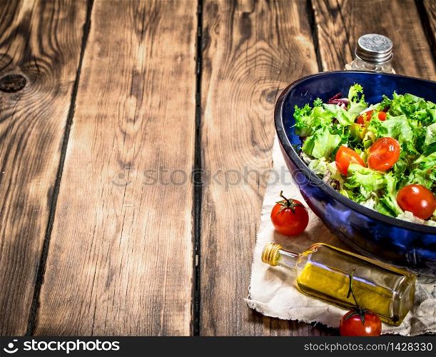 Salad with tomatoes and fresh greens with olive oil. On a wooden table. Salad with tomatoes and greens