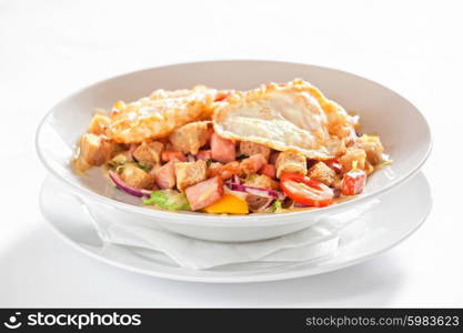 salad with vegetables, bacon and fried eggs on white background