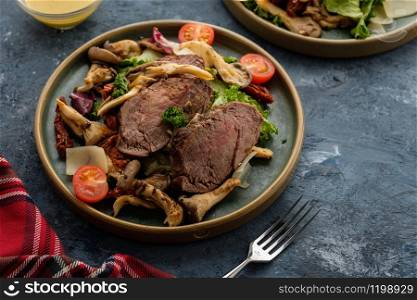 Salad with warm beef with oyster mushrooms, tomatoes and greens