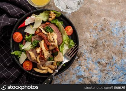 Salad with warm beef with oyster mushrooms, tomatoes and greens. Top view.