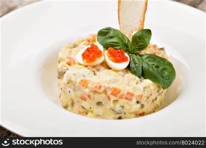 Salade Olivier decorated with red caviar, mayonnaise