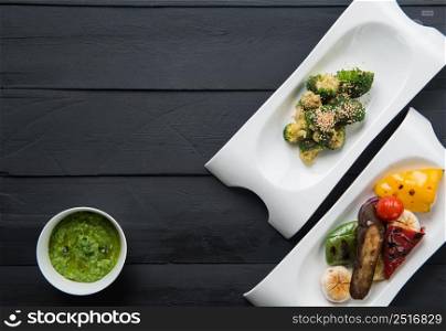 salads and vegetable food in plates on a black wooden background. the food, the view from the top