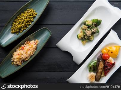 salads and vegetable food in plates on a black wooden background. the food, the view from the top
