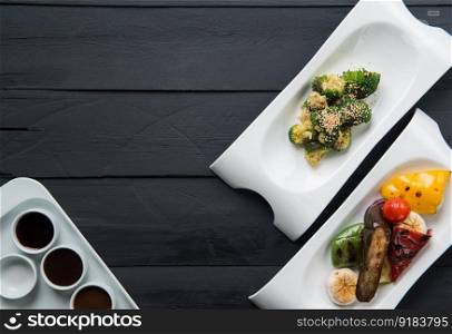 salads, vegetable food and sauces in plates on a black wooden background. the food, the view from the top