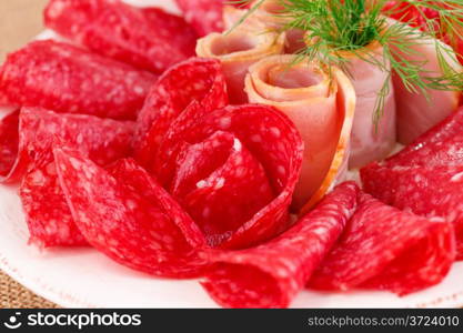 Salami and bacon on plate closeup image.