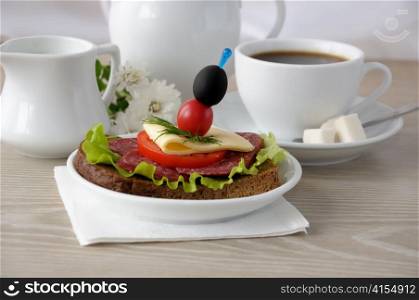 Salami sandwich and a cup of coffee with milk in the milkman