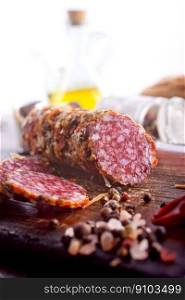 Salami sausage with slices on wooden board. Salami sausage with slices on wooden board on a table