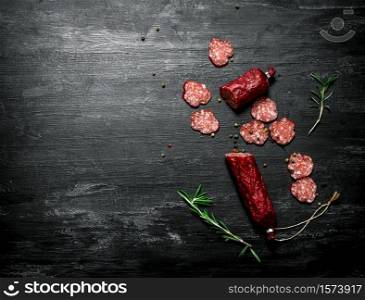 Salami with fresh rosemary and spices. On black rustic background.. Salami with fresh rosemary and spices.