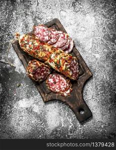 Salami with spices and herbs. On a rustic background.. Salami with spices and herbs.
