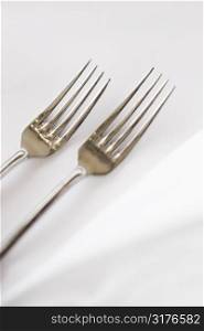 Sald fork and dinner fork on white table cloth.