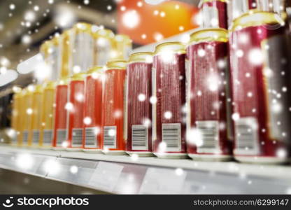 sale and alcohol concept - close up of beer or cider cans at liquor store over snow. close up of beer or cider cans at liquor store