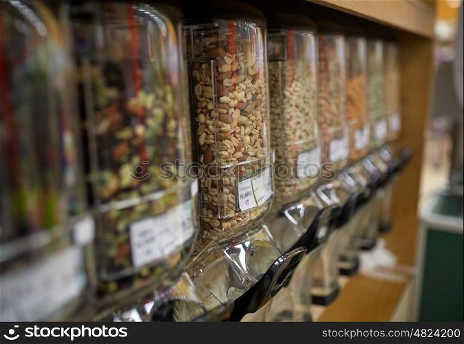 sale and eco food concept - row of jars with nuts and seeds at grocery store. row of jars with nuts and seeds at grocery store