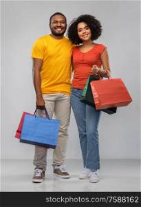 sale and people concept - happy african american couple with shopping bags over grey background. happy african american couple with shopping bags