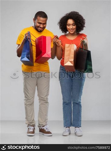sale and people concept - happy african american couple with shopping bags over grey background. happy african american couple with shopping bags