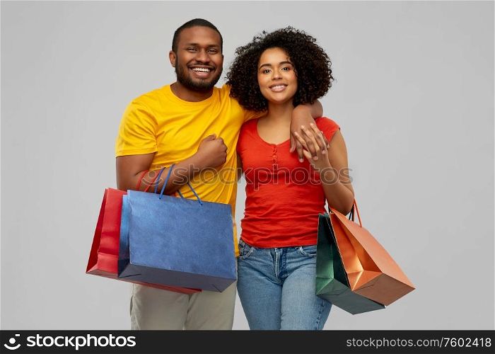 sale and people concept - happy smiling african american couple with shopping bags over grey background. happy african american couple with shopping bags