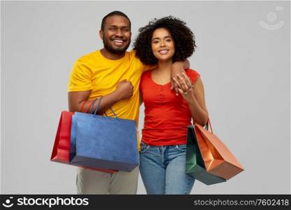sale and people concept - happy smiling african american couple with shopping bags over grey background. happy african american couple with shopping bags