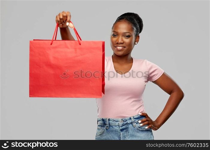 sale and people concept - happy smiling african american young woman with shopping bag over grey background. happy african american woman with shopping bag