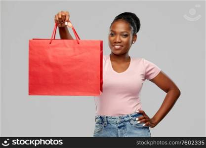 sale and people concept - happy smiling african american young woman with shopping bag over grey background. happy african american woman with shopping bag