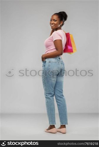 sale and people concept - happy smiling african american young woman with shopping bags over grey background. happy african american woman with shopping bags