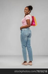 sale and people concept - happy smiling african american young woman with shopping bags over grey background. happy african american woman with shopping bags