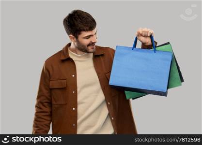 sale and people concept - happy smiling young man with shopping bags over grey background. happy smiling young man with shopping bags