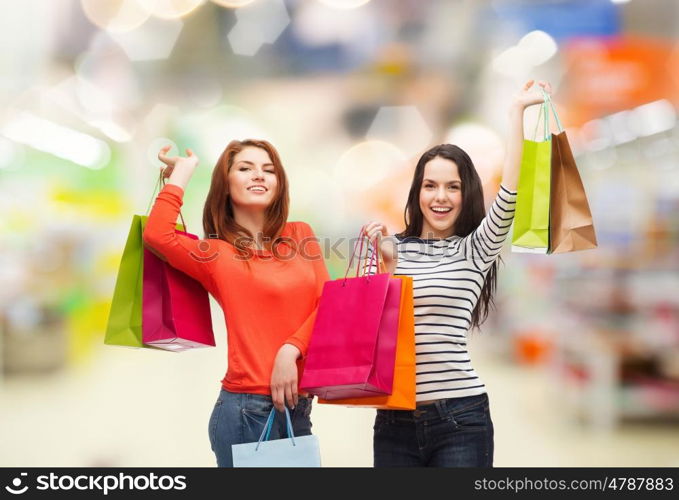 sale and people concept - two smiling teenage girls with shopping bags over supermarket background. teenage girls with shopping bags and credit card