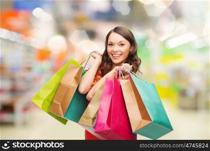 sale and people - smiling woman with colorful shopping bags over supermarket background. woman with shopping bags at store