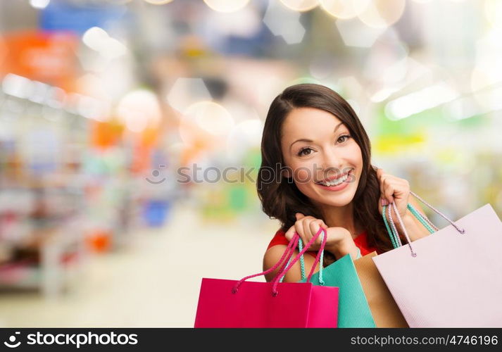 sale and people - smiling woman with colorful shopping bags over supermarket background. woman with shopping bags at store