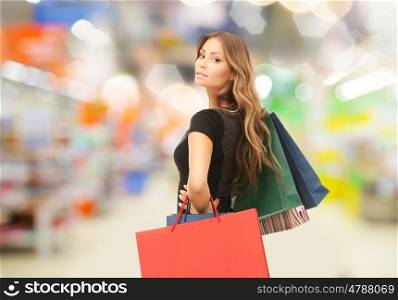 sale and people - woman with colorful shopping bags over supermarket background. woman with shopping bags at store or supermarket