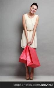 Sale and retail. Young woman girl with red shopping bags in hands on grey background in studio.