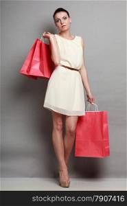 Sale and retail. Young woman girl with red shopping bags in hands on gray background in studio.