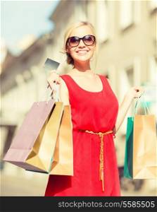 sale and tourism, happy people concept - beautiful blonde woman with shopping bags in the ctiy