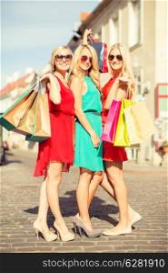 sale and tourism, happy people concept - beautiful blonde women with shopping bags in the ctiy