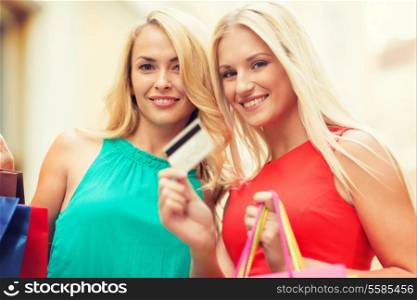 sale and tourism, happy people concept - beautiful women with shopping bags and credit card in the ctiy