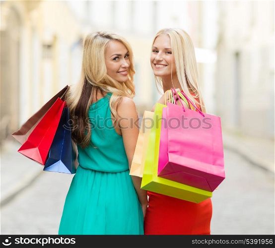 sale and tourism, happy people concept - beautiful women with shopping bags in the ctiy