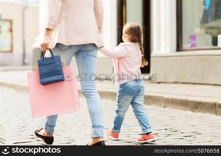 sale, consumerism and people concept - close up of mother and child with shopping bags walking along city street