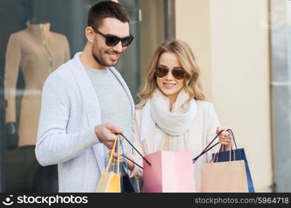 sale, consumerism and people concept - happy couple looking into shopping bag at shop window on city street