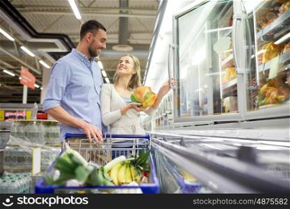 sale, consumerism and people concept - happy couple with shopping cart buying frozen food at grocery store or supermarket