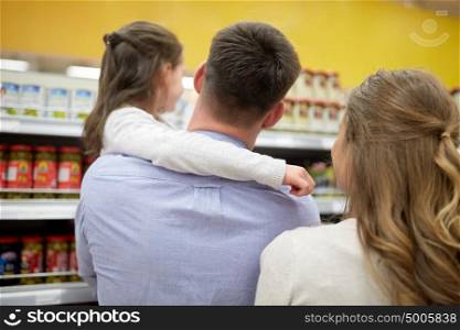 sale, consumerism and people concept - happy family with child and shopping cart buying food at grocery store or supermarket. family buying food and shopping at grocery store